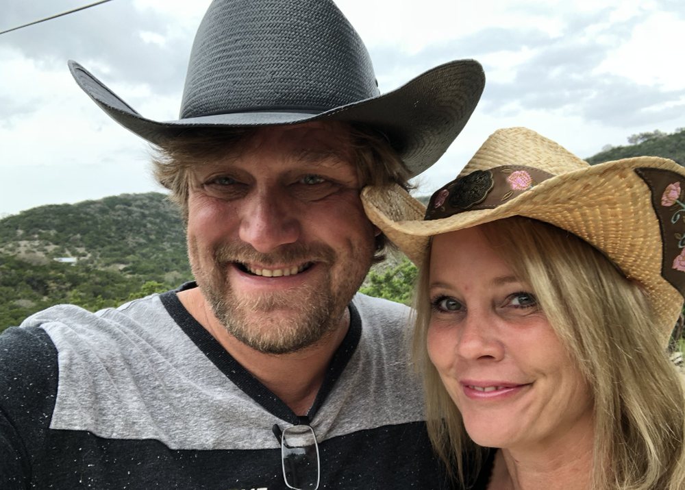 Spencer and Jess in cowboy hats with the hills behind them